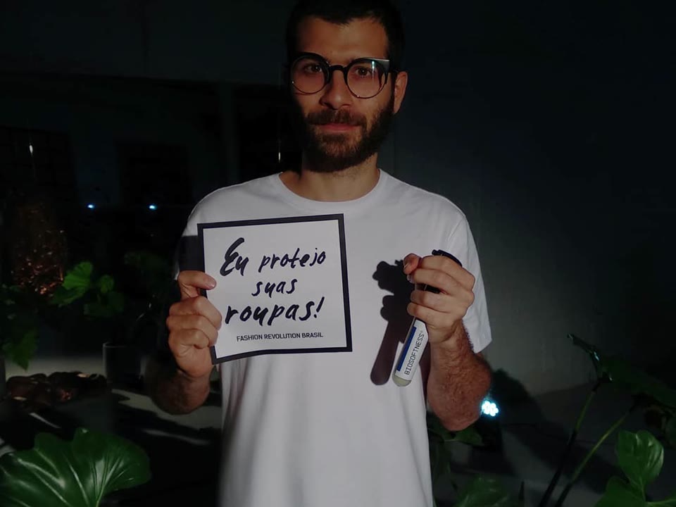 Renan Serrano segurando o frasco do Biosoftness e uma placa escrita Eu protejo suas roupas