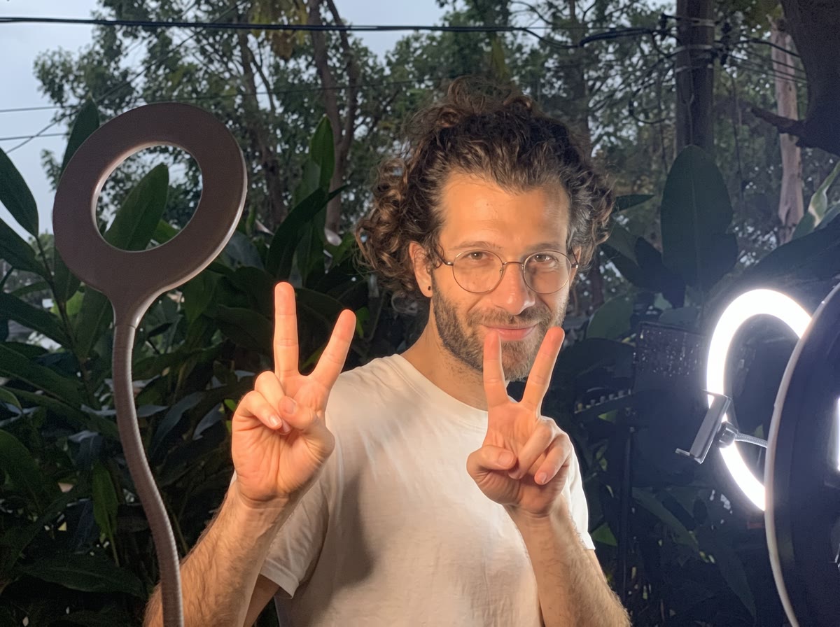 Renan Serrano fazendo sinal de paz e amor, com luzes de gravação ao fundo